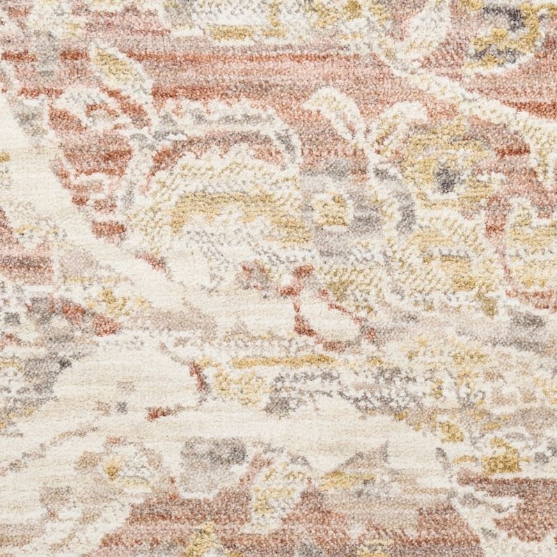 A close-up of a textured area rug featuring an abstract, distressed floral pattern in muted tones of terracotta, beige, cream, and gray.