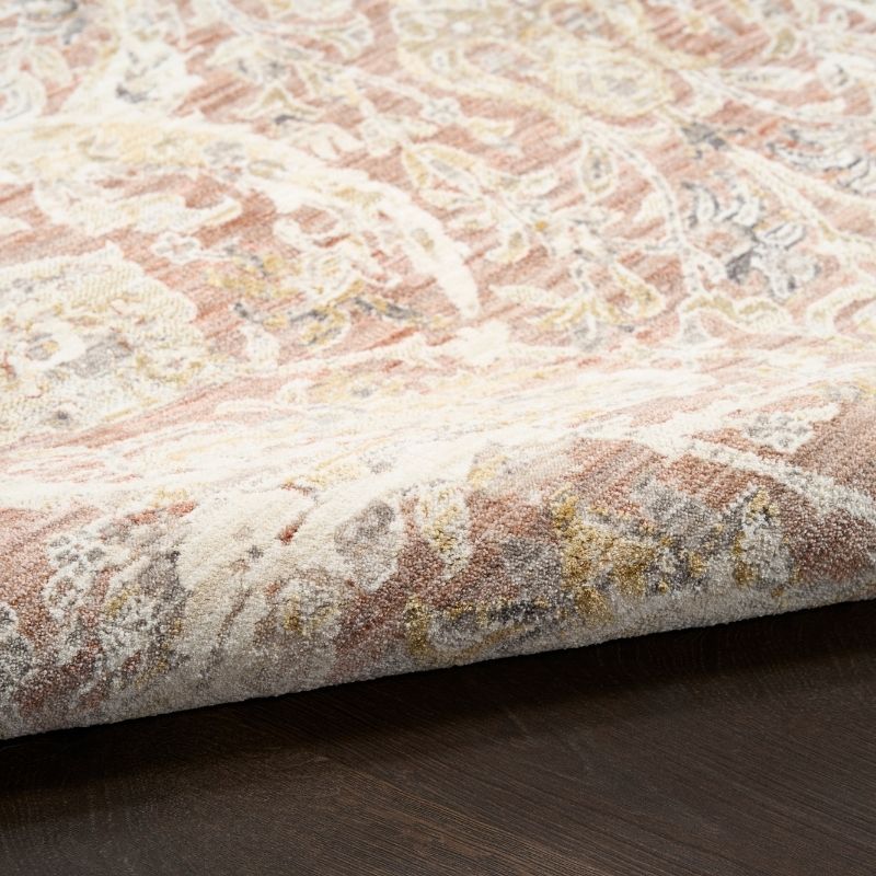Close-up of a textured area rug with intricate patterns on a wooden floor.