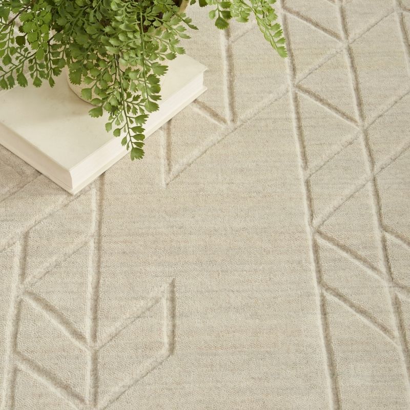 Textured beige carpet with geometric pattern and a book with green leaves on top.
