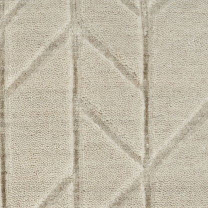 A close-up of a textured fabric or carpet in a warm off-white/cream tone with a subtle geometric pattern formed by slightly raised lines.