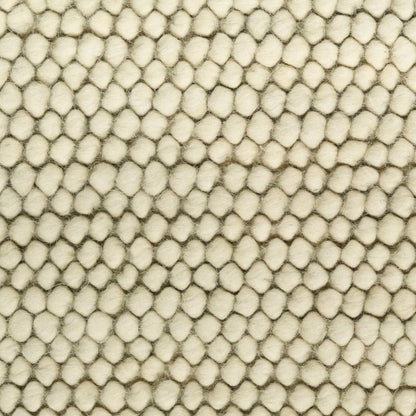 A close-up texture shot of a cream-colored fabric with a raised, hexagonal or honeycomb-like tufted pattern.
