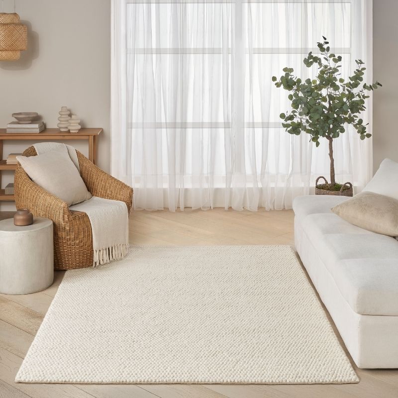 Living room with a white rug, wicker chair, and white sofa.