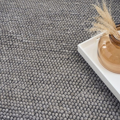 Gray textured carpet with a white shelf and decorative items.