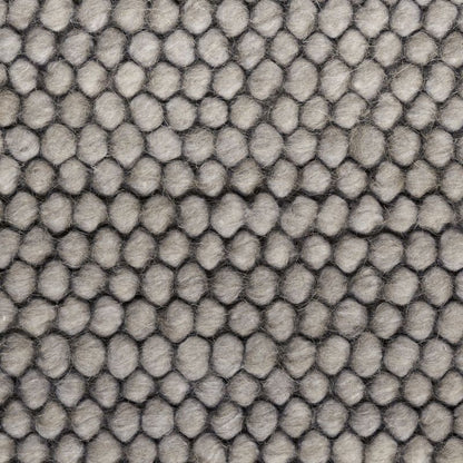 Close-up of a gray textured fabric with a repeating hexagonal or honeycomb-like raised pattern.