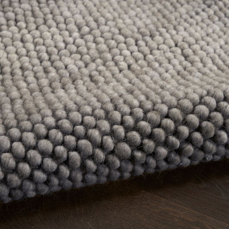 Close-up of a textured gray rug on a wooden floor