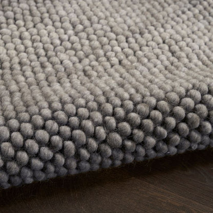 Close-up of a textured gray rug on a wooden floor
