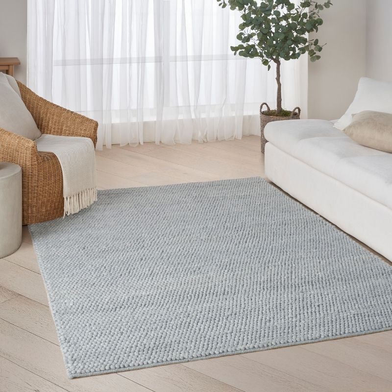 Living room with a light blue rug, white sofa, and wicker chair.