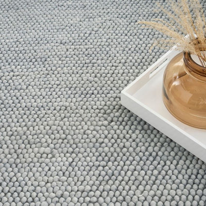 Textured gray rug with a small decorative item on a white surface