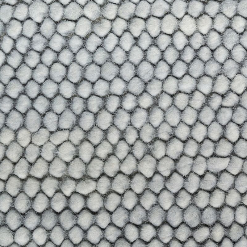 A close-up of a textured fabric or material with a repeating scale-like pattern in light gray and white.