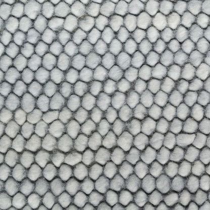 A close-up of a textured fabric or material with a repeating scale-like pattern in light gray and white.