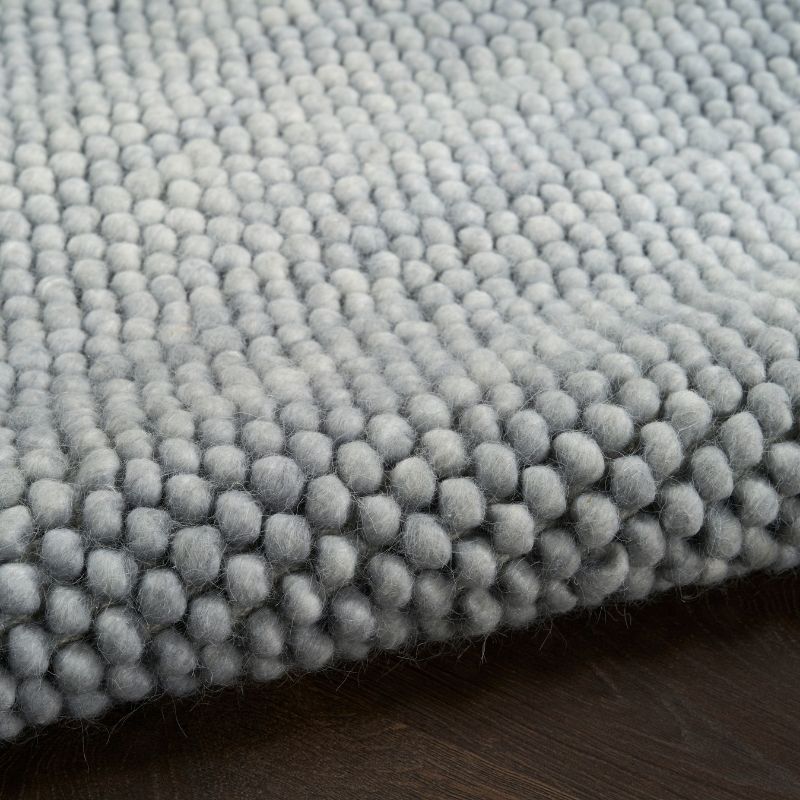 Close-up of a textured gray rug on a wooden floor