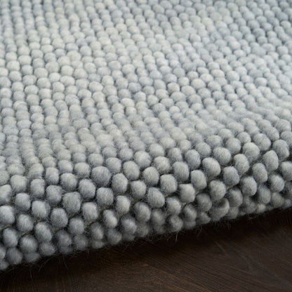Close-up of a textured gray rug on a wooden floor