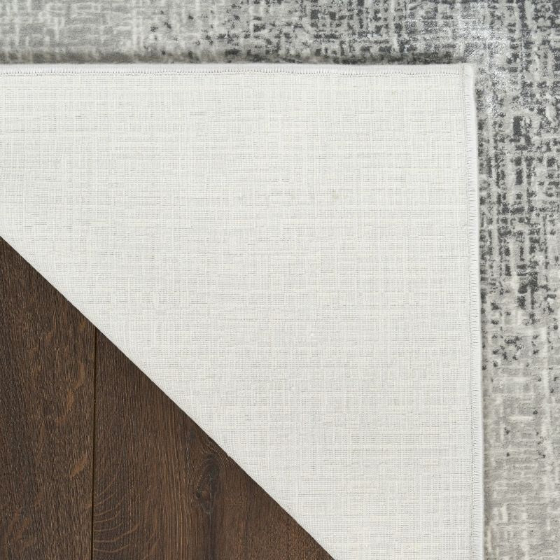 Close-up of a rug with a textured border on a wooden floor.