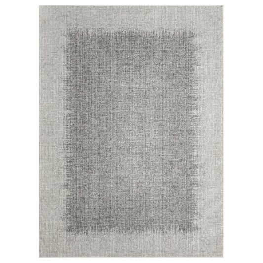A rectangular area rug with a textured, distressed pattern in shades of gray, featuring a darker gray central panel surrounded by a lighter gray border.