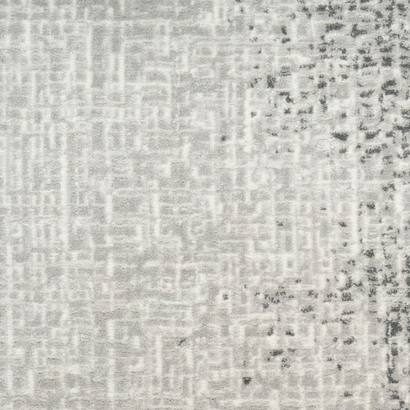 A close-up of a textured fabric or wallpaper pattern in light gray and white with darker gray distressed speckling concentrated on the right side.