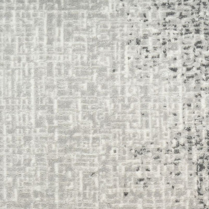 A close-up of a textured fabric or wallpaper pattern in light gray and white with darker gray distressed speckling concentrated on the right side.
