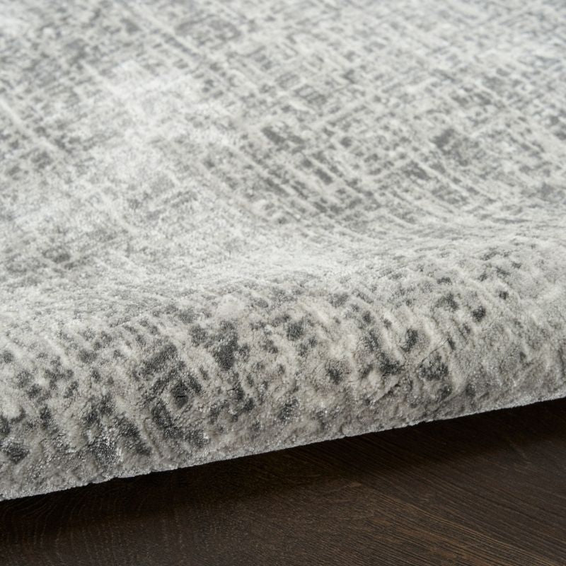 Close-up of a textured gray rug with a subtle pattern on a dark wooden floor.
