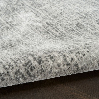 Close-up of a textured gray rug with a subtle pattern on a dark wooden floor.