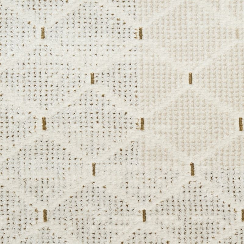 A close-up of a textured fabric with a cream and off-white woven pattern featuring small vertical brown stitched accents.