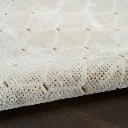 Close-up of a textured white surface with small brown specks on a dark wooden floor.