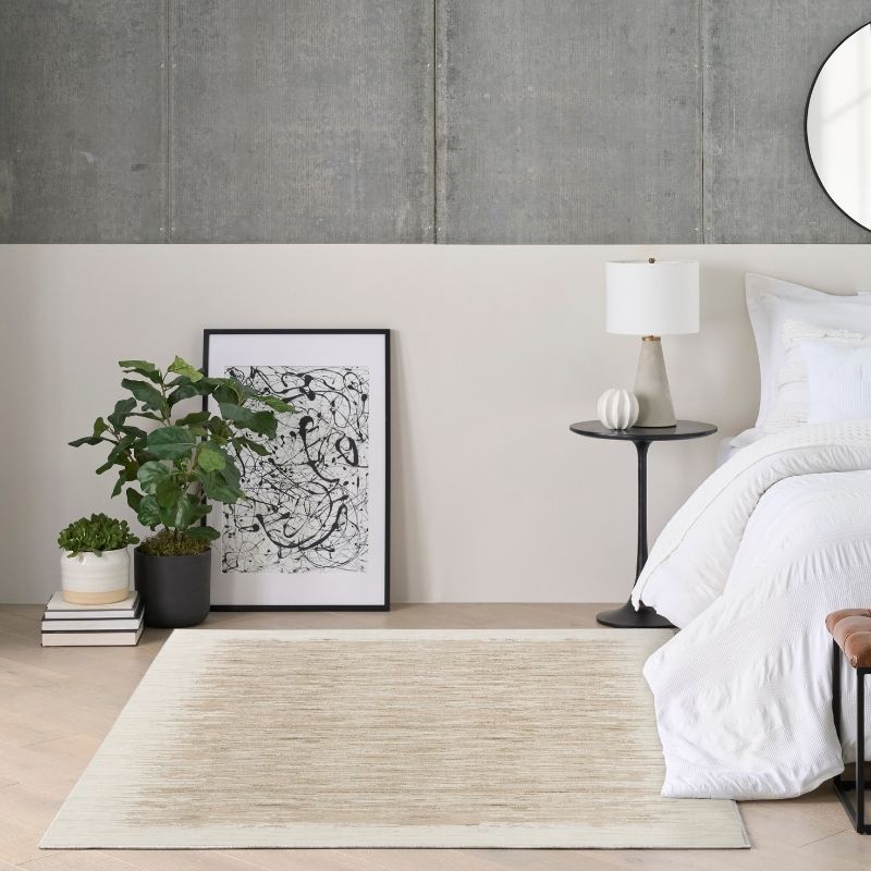 Modern bedroom with a bed, side table, lamp, and decorative items.