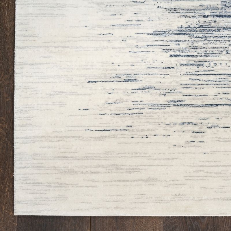 Close-up of a textured rug with white and blue pattern on a wooden floor.