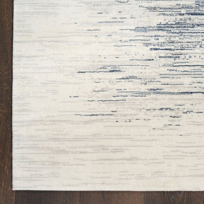 Close-up of a textured rug with white and blue pattern on a wooden floor.