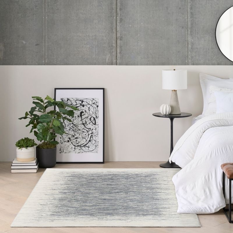 Modern bedroom with a bed, side table, lamp, and decorative items.