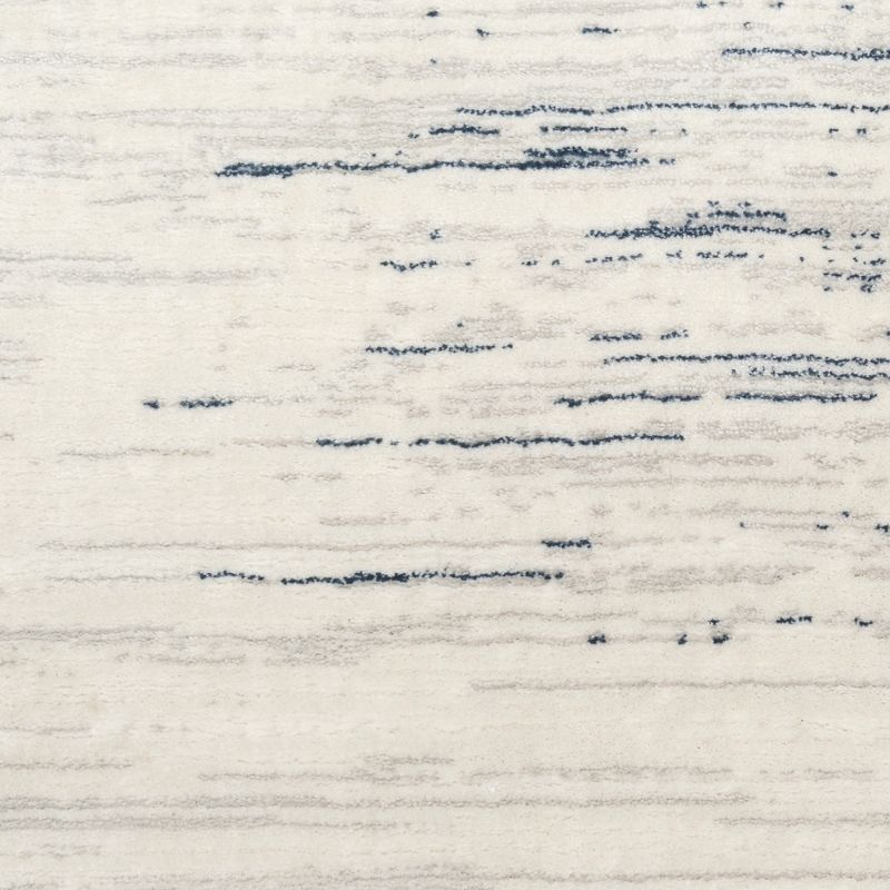 A close-up of a textured rug or fabric with a distressed abstract pattern in dark navy blue on an off-white background.