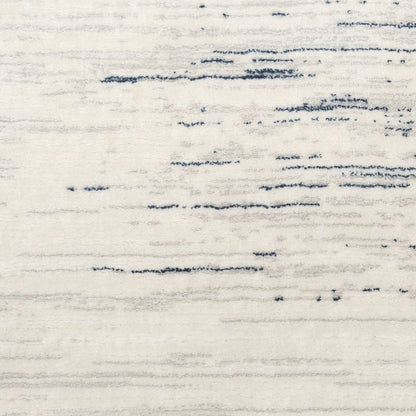 A close-up of a textured rug or fabric with a distressed abstract pattern in dark navy blue on an off-white background.