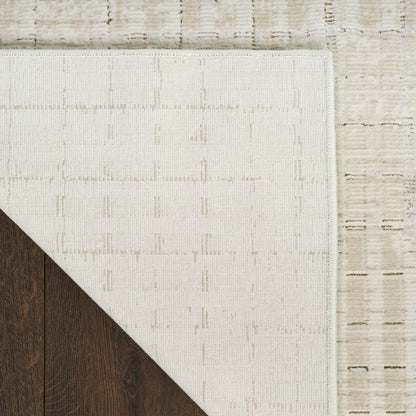 Close-up of a textured white rug corner on a wooden floor.