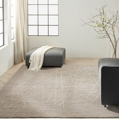 Living room with a patterned rug, gray ottoman, and modern decor.