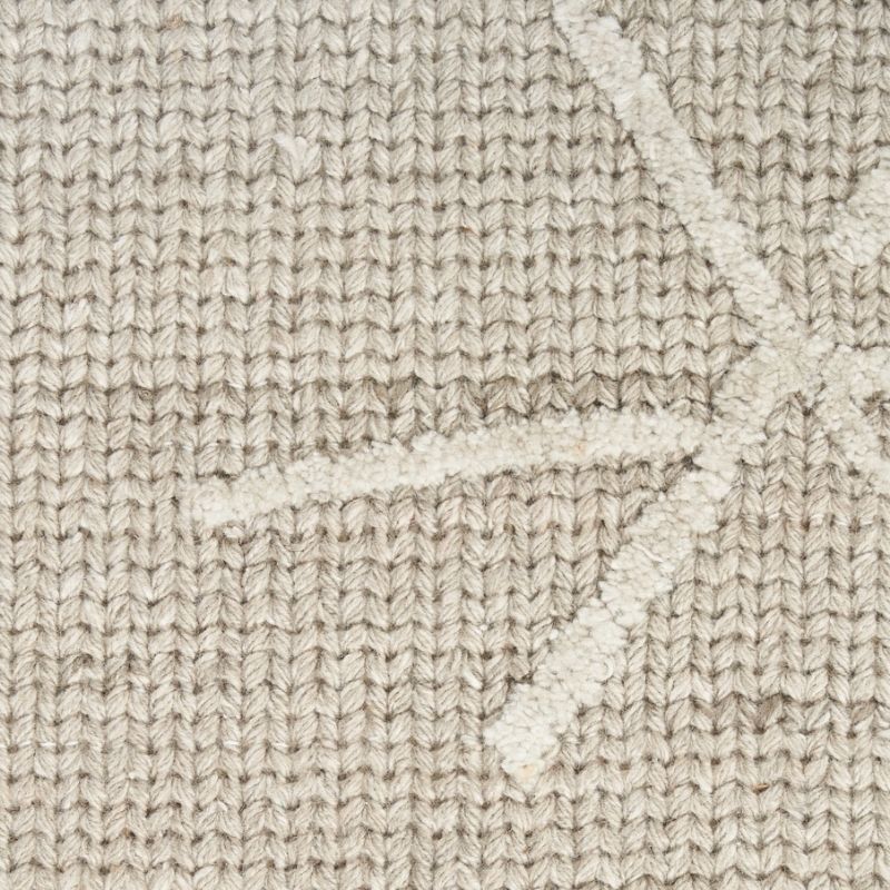 Close-up of a textured knit fabric in a warm beige or oatmeal tone, showing a subtle raised geometric star-like pattern.