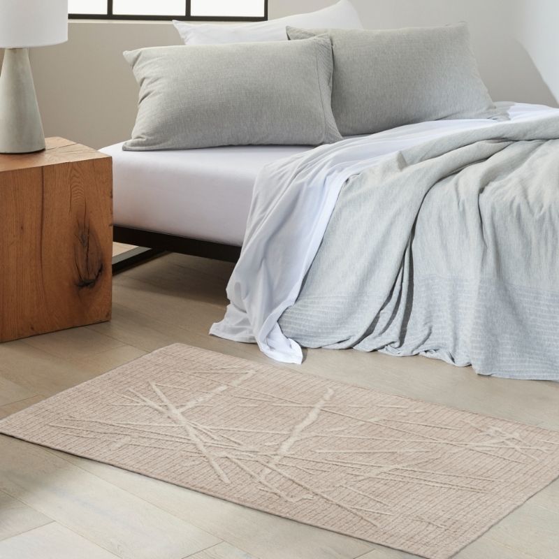 Neatly made bed with gray bedding on a wooden nightstand in a bedroom.