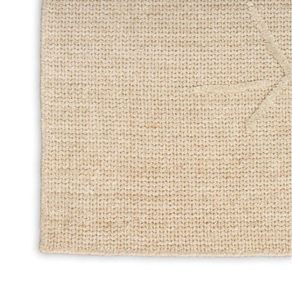 A close-up of a textured woven rug in a natural beige color, showing the detailed knit pattern and folded corner on a white background.