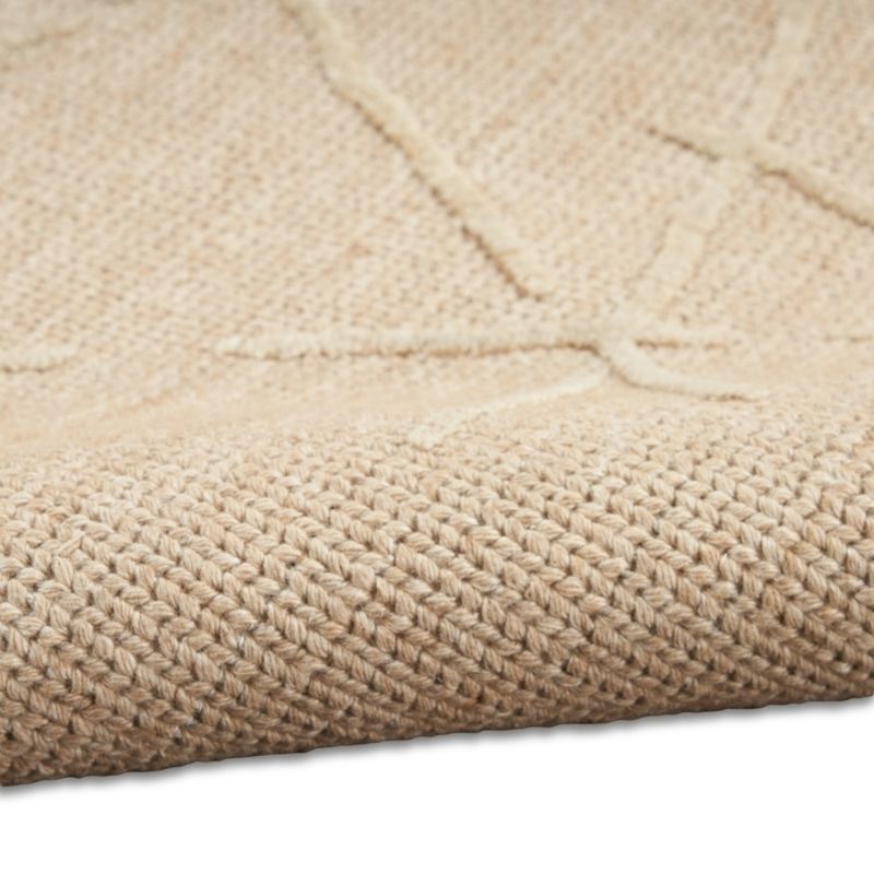 Close-up of a woven natural fiber rug in a light beige color, showing the detailed texture and a subtle geometric pattern.