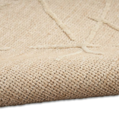 Close-up of a woven natural fiber rug in a light beige color, showing the detailed texture and a subtle geometric pattern.