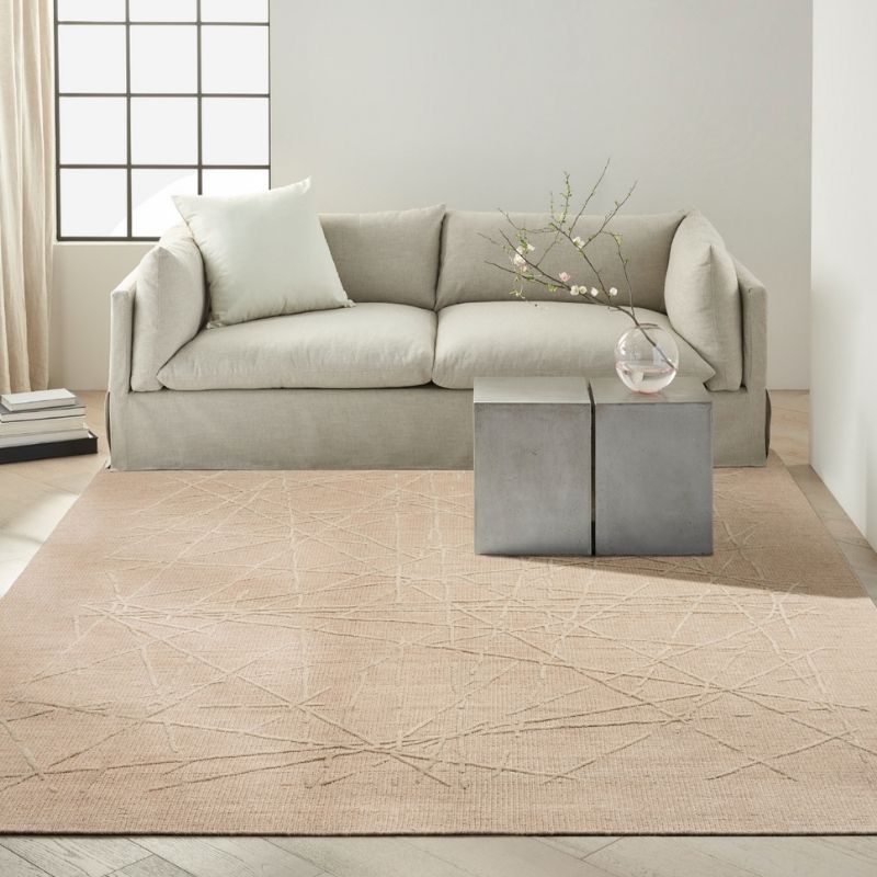 Beige sectional sofa in a modern living room with a patterned rug.