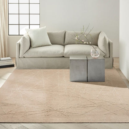 Beige sectional sofa in a modern living room with a patterned rug.