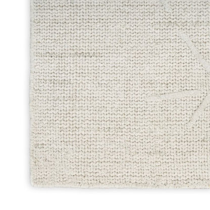 Close-up of a textured off-white woven fabric or rug showing the knit pattern and corner detail against a white background.