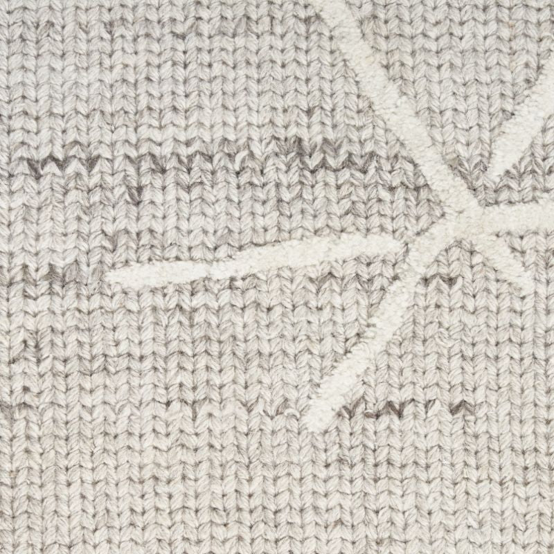 Close-up of a textured knit fabric in a light oatmeal beige color, featuring a subtle white geometric starburst pattern.
