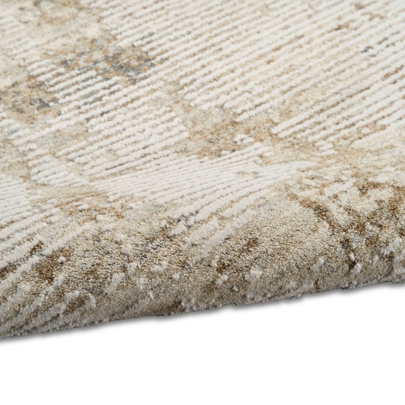 Close-up of a textured area rug with a beige and cream geometric pattern, showing the pile and corner detail against a white background.
