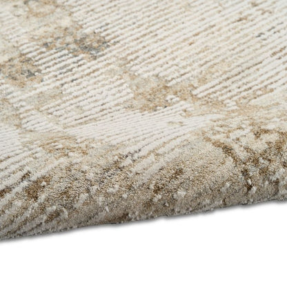Close-up of a textured area rug with a beige and cream geometric pattern, showing the pile and corner detail against a white background.