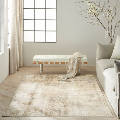 A rectangular area rug with a distressed, faded cream and beige pattern, styled in a bright, modern living room next to a light gray sofa and a white tufted bench.