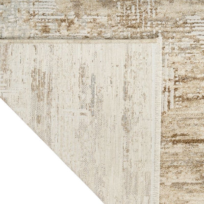 Close-up of a textured area rug corner showing a distressed traditional pattern in cream, beige, and taupe tones, with a white corner overlay.