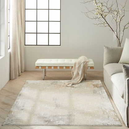 A large rectangular area rug in a neutral cream, beige, and light gray distressed pattern, styled in a bright, modern living room next to a sofa and a bench.