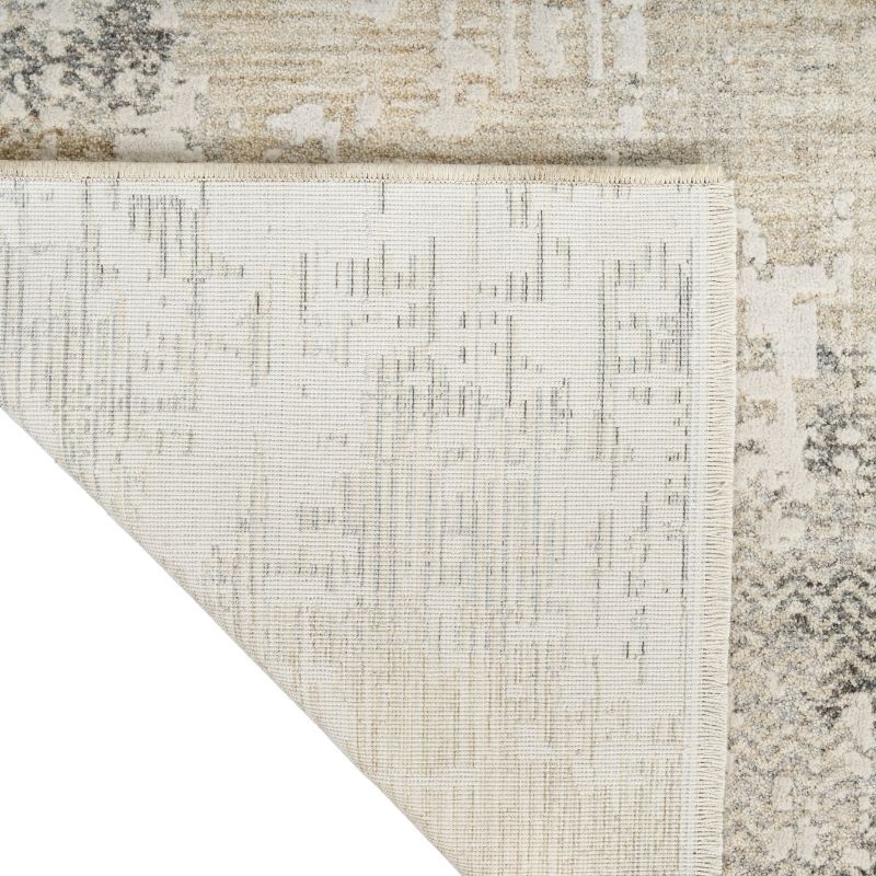 Close-up of a textured area rug corner showing a distressed abstract pattern in cream, beige, and gray tones, with a white corner overlay.