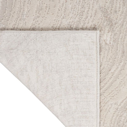 Close-up of a light beige textured rug corner with a white underside visible, showing the pile and woven edge detail.