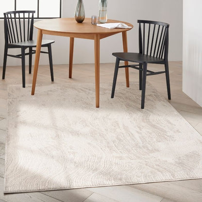 A large off-white area rug with a subtle wavy pattern, shown in a dining room setting under a round wooden table and two black chairs.