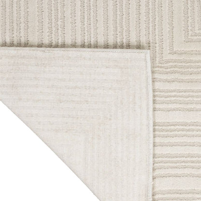 Close-up of a light beige textured rug corner showing a striped pattern and a white underside backing.